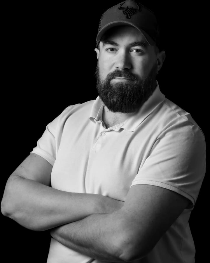 Kevin Machy, portrait en noir et blanc sur fond noir, bras croisés